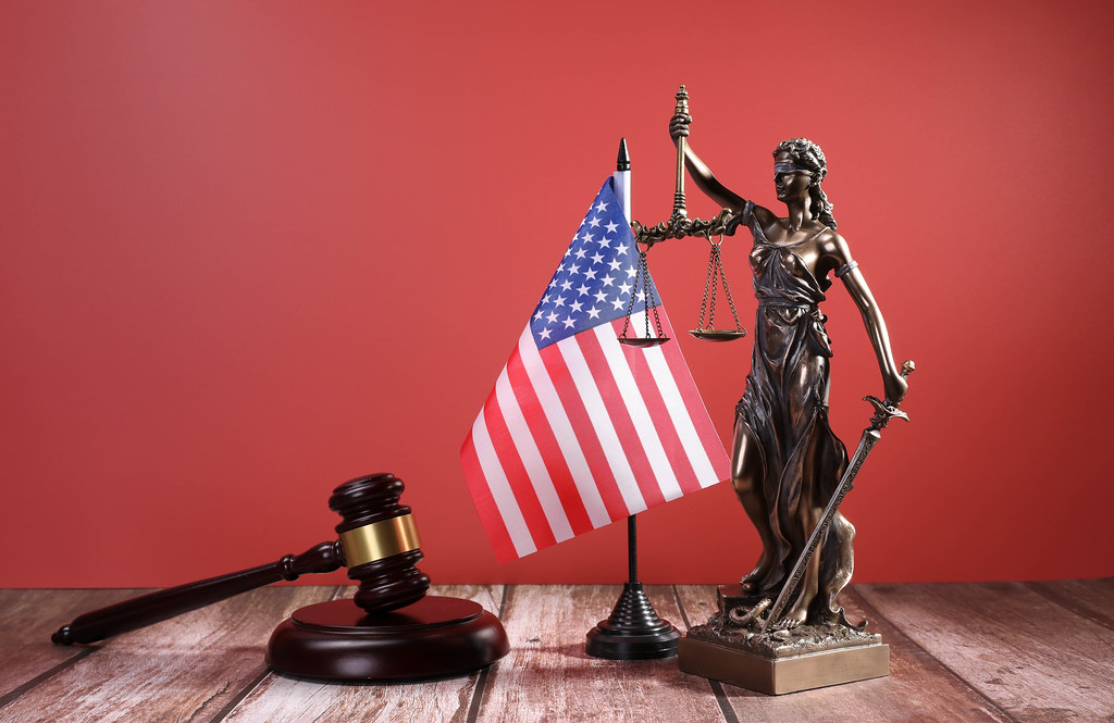 Statue of Lady Justice with Judge gavel and flag of USA