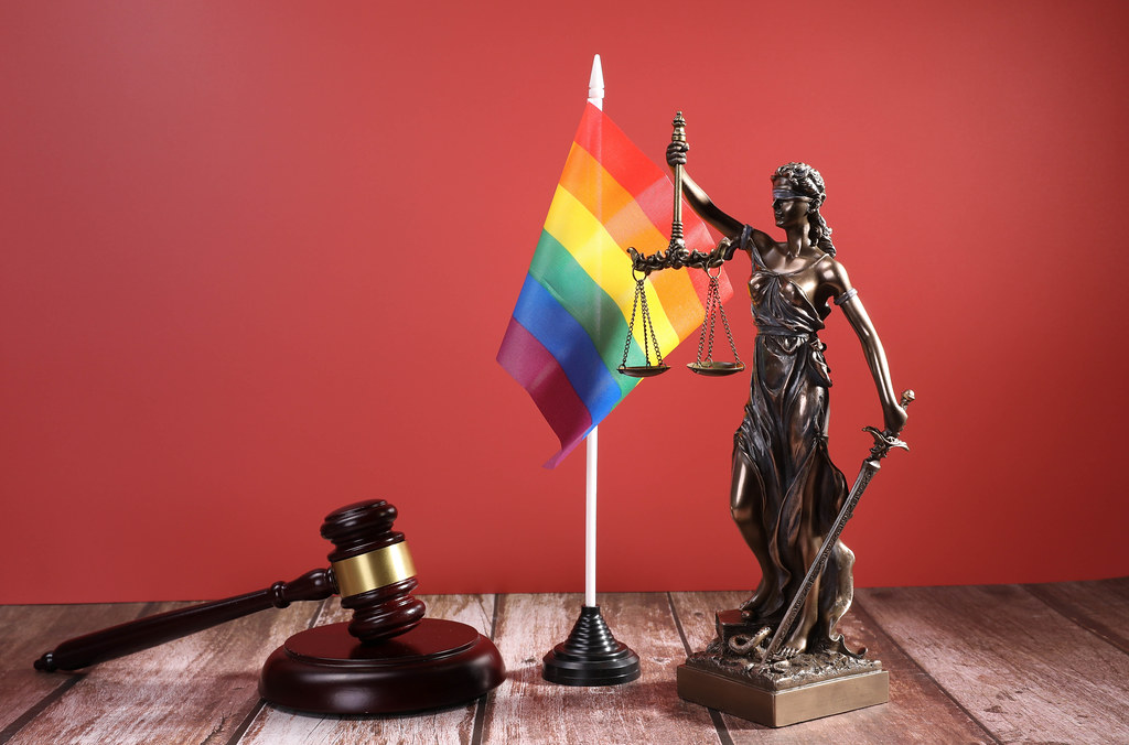 Statue of Lady Justice with Judge gavel and rainbow flag