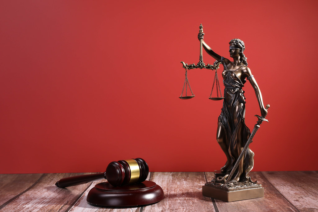 Statue of Lady Justice with Judge gavel on red background