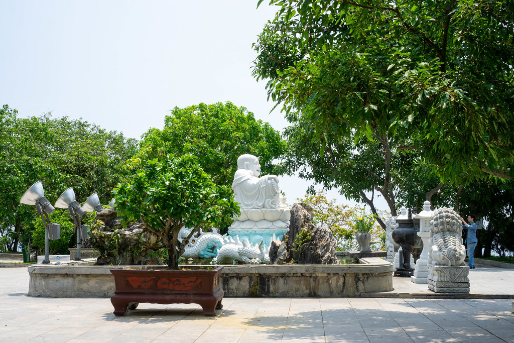 Statues of White Laughing Buddha, Chinese Guardian Lions and a Dragon in front of Lady Buddha Statue at Linh Ung Pagoda in Da Nang, Vietnam