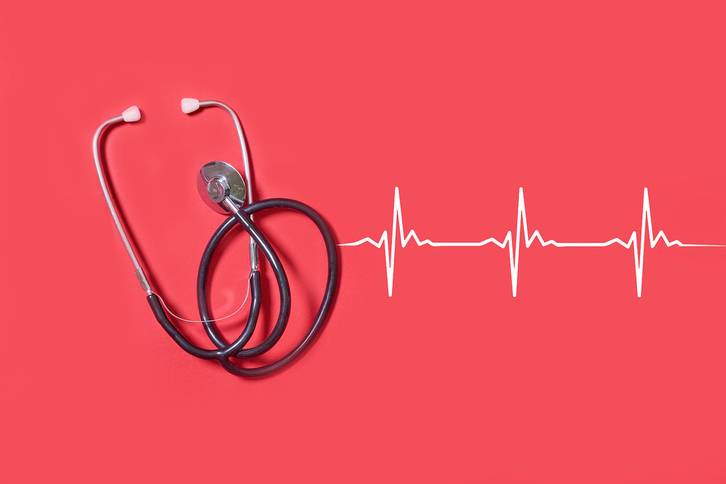 Stethoscope and heartbeats on red