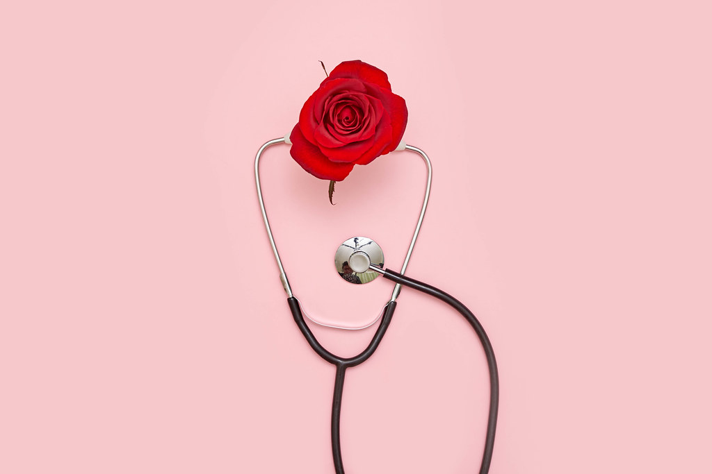 Stethoscope and rose flower on pink background
