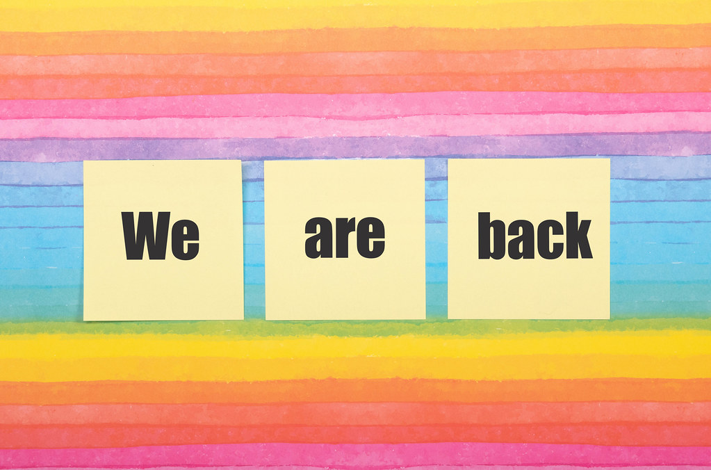 Sticky notes with We are back text on colorful background