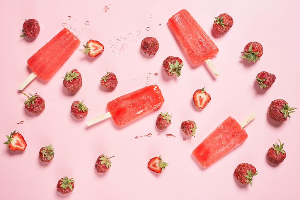 Strawberry vanilla ice cream popsicle on strawberry fruits