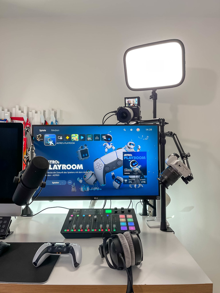 Streaming setup with monitor showing Astro's Playroom, cameras, microphone, controller, headphones
