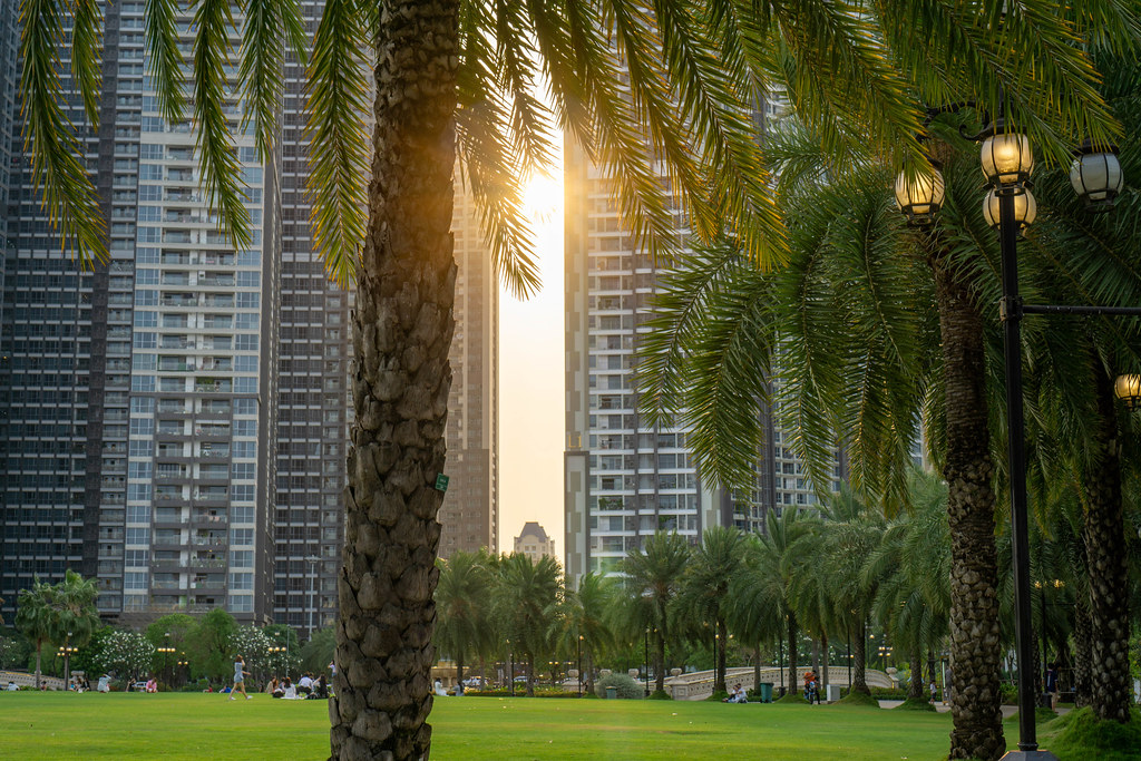 Sunset behind Vinhomes Apartment Buildings at Vinhomes Central Park with Palm Trees and Big Lawn in Ho Chi Minh City, Vietnam