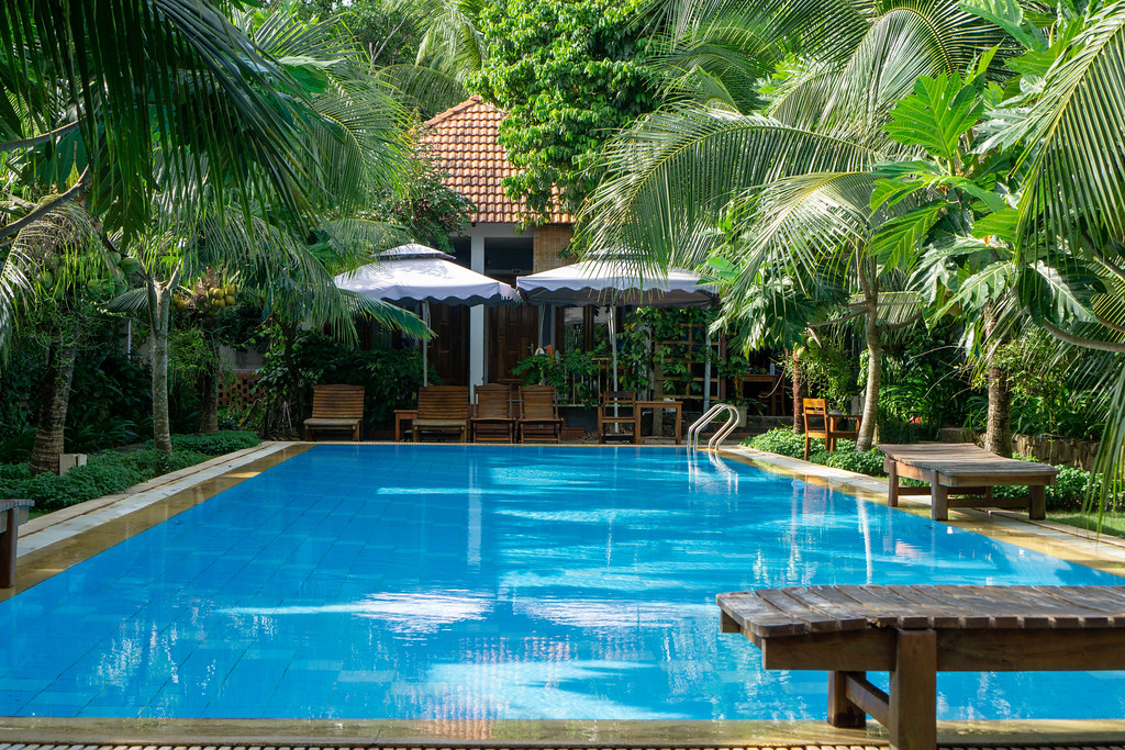 Swimming Pool with Sunbeds and Garden at a Hotel with many Villas and Palm Trees on Phu Quoc Island, Vietnam