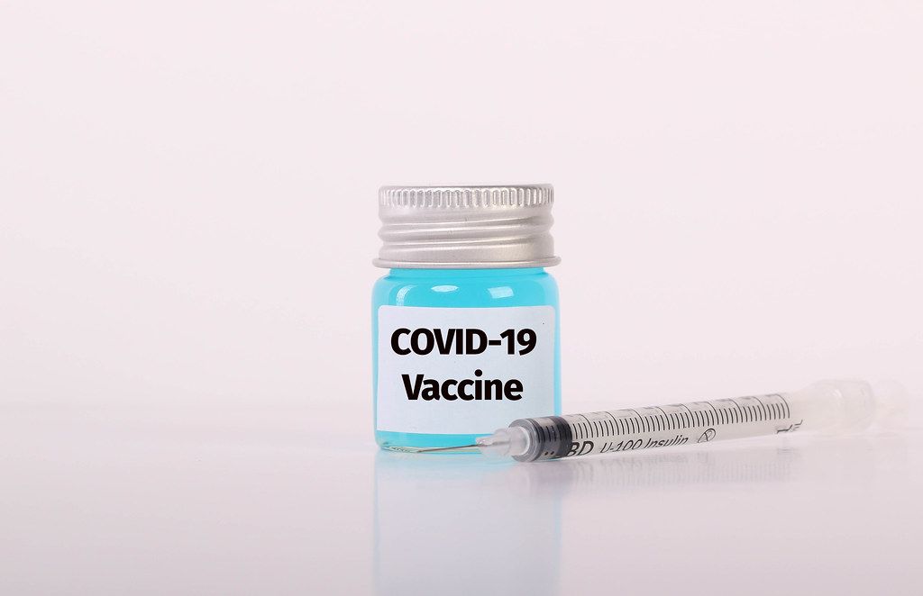 Syringe and bottle with blue fluid and Covid-19 Vaccine text