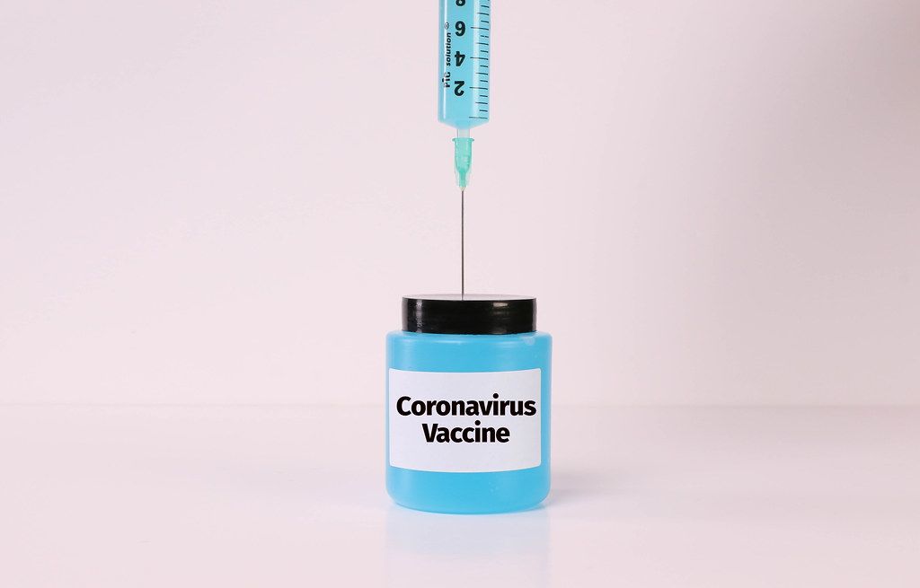 Syringe and bottle with fluid and Coronavirus Vaccine text on white background