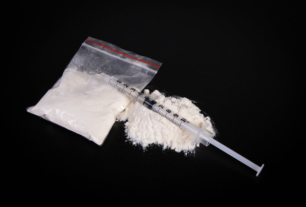 Syringe and cocaine on black background