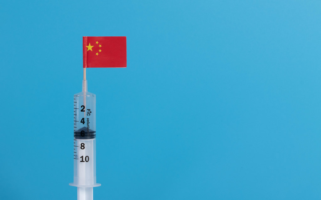 Syringe with flag of China on blue background