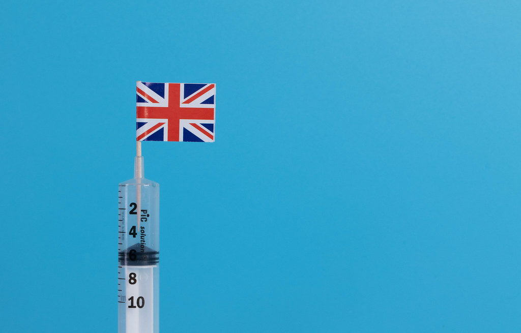Syringe with flag of UK on blue background