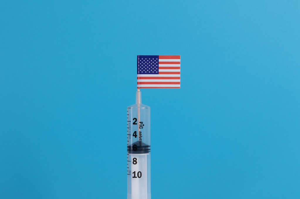 Syringe with flag of United States of America on blue background