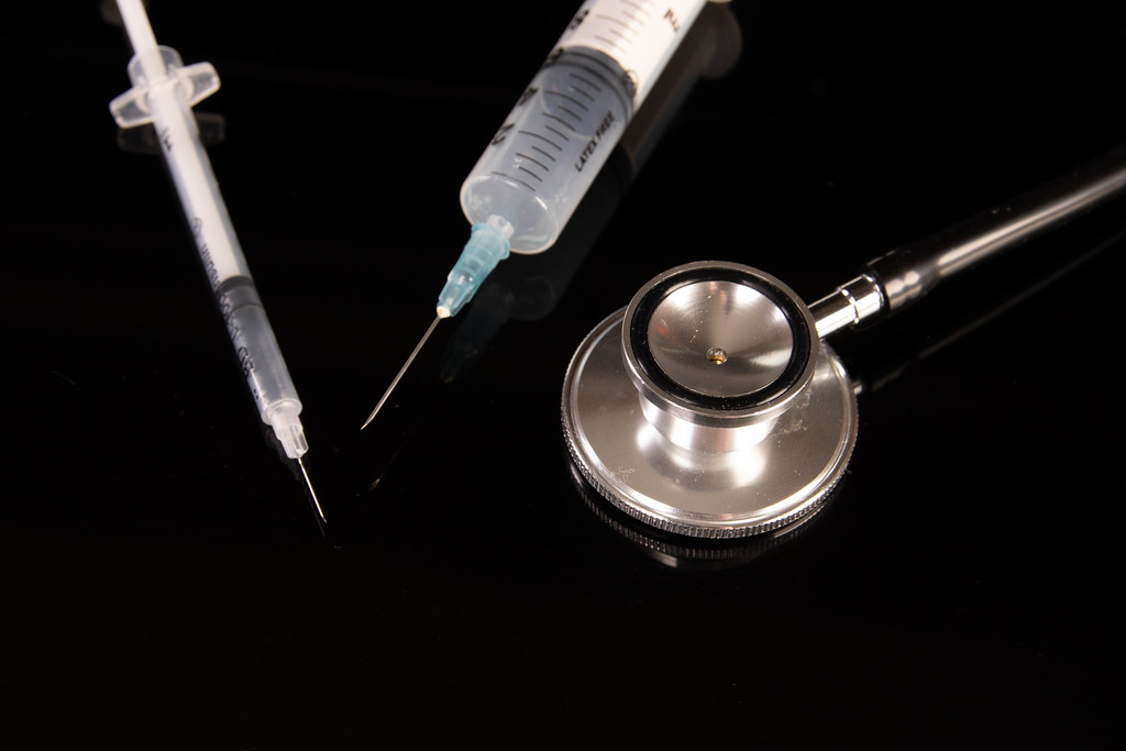 Syringes and stethoscope on black background