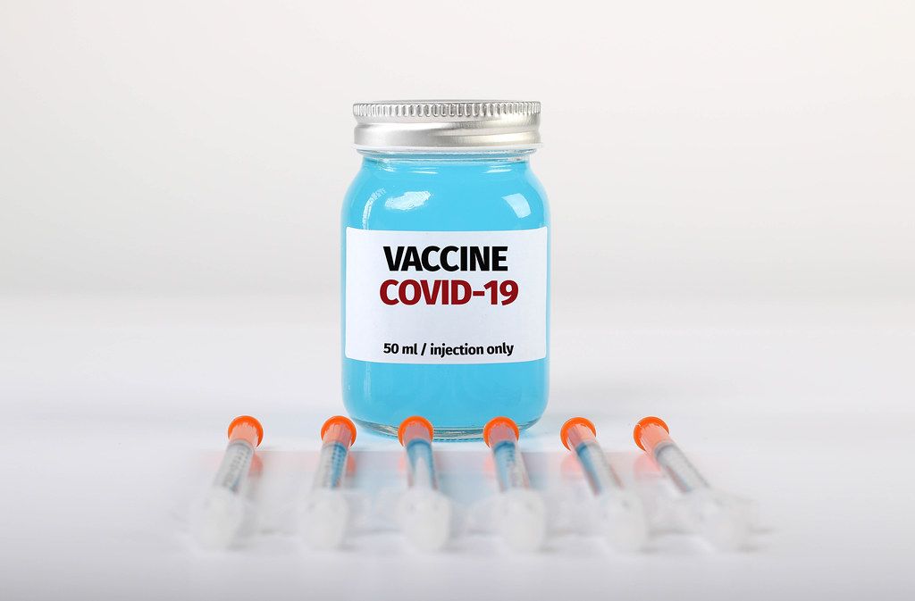 Syringes with bottle with Covid-19 vaccine on white background