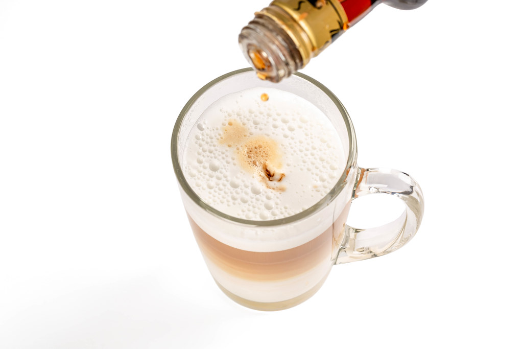 Syrup is poured into a fresh latte with foam