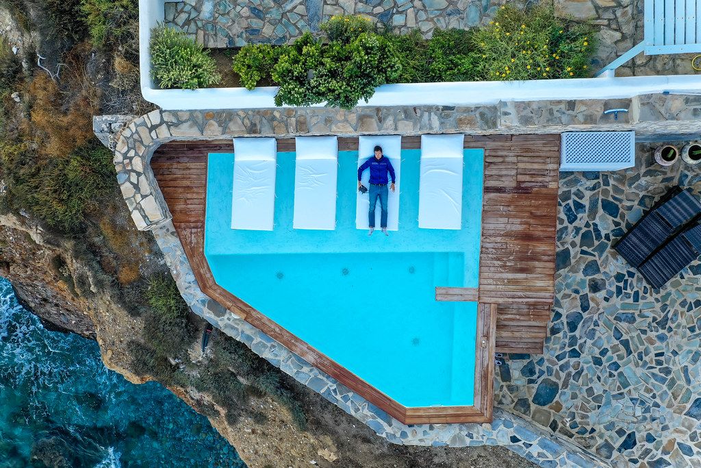 Taking aerial photos while lying with the drone controller by the pool at Iliada Suites hotel in Naxos