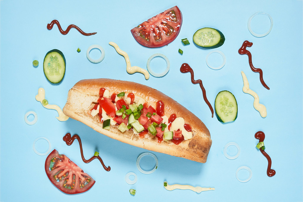 Tasty hotdog and ingredients on blue background