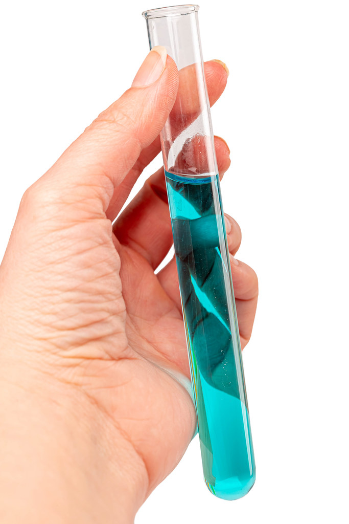 Test tube with blue solution in female hand, research concept