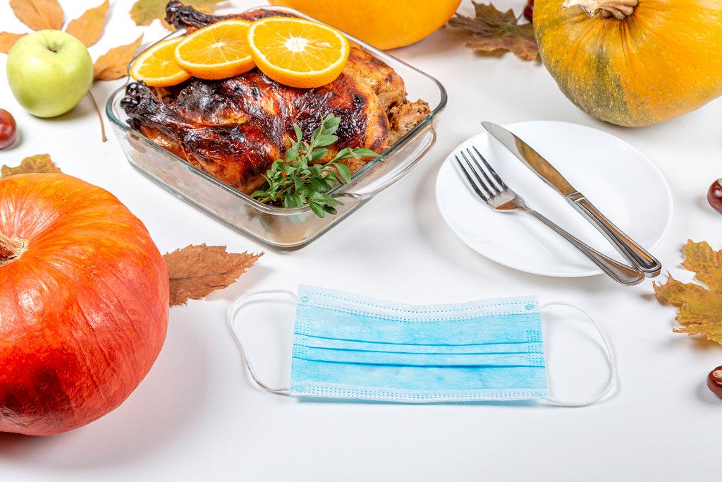 Thanksgiving background with fried chicken, pumpkin, leaves, cutlery and medical mask