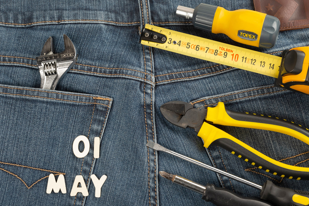 The concept of labor day-the first of may made of wooden letters on the background of jeans with hand tools