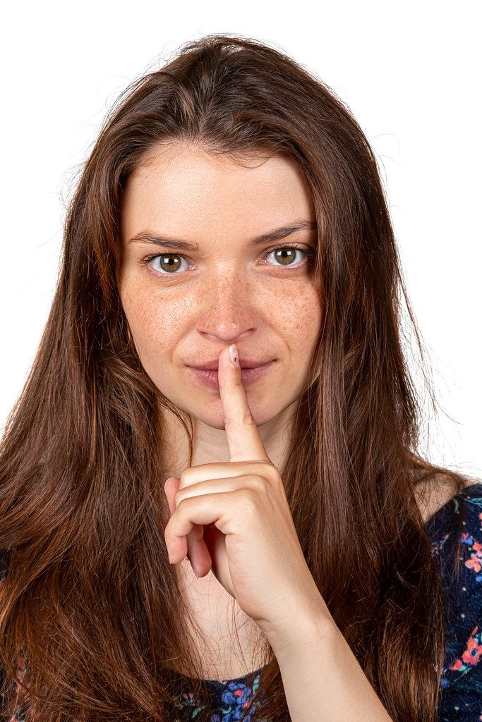 The concept of silence. Girl's face with finger near lips