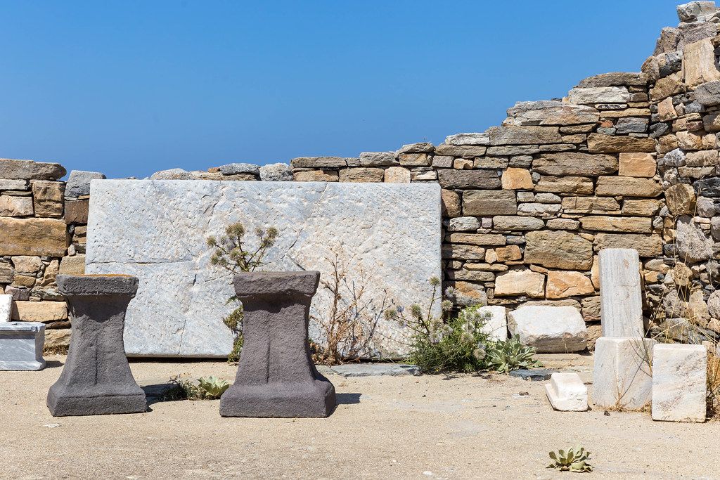 The ruins of Delos, ancient Greek site in the Cyclades. Stone wall, pillars and marble slab