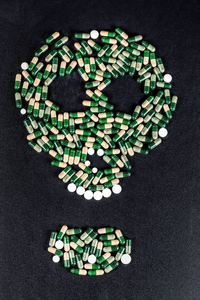 The skull on a black background is made of tablets and capsules. The concept of death