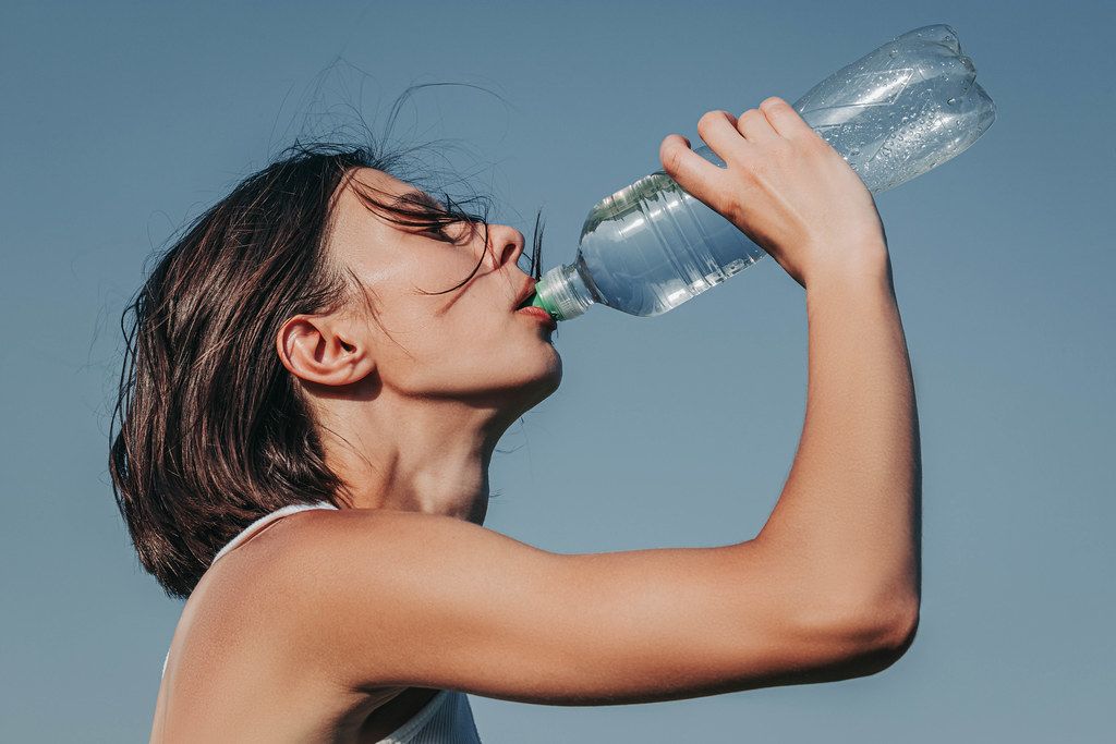 Thirsty fitness girl drink water from bottle