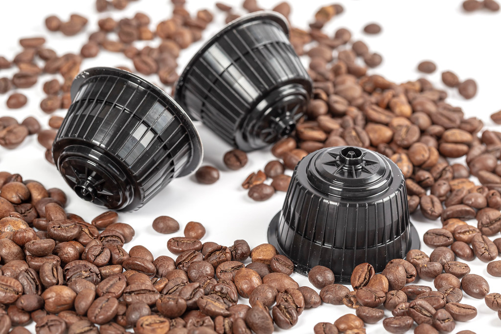 Three coffee capsules with pressed coffee and roasted coffee beans