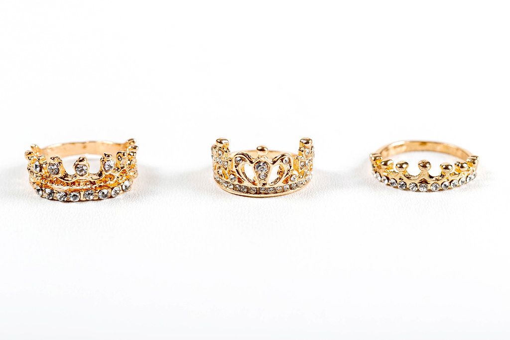 Three crown-shaped rings with stones on a white background