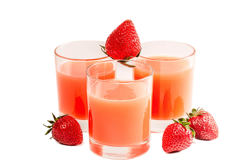 Three glasses of juice and ripe strawberries