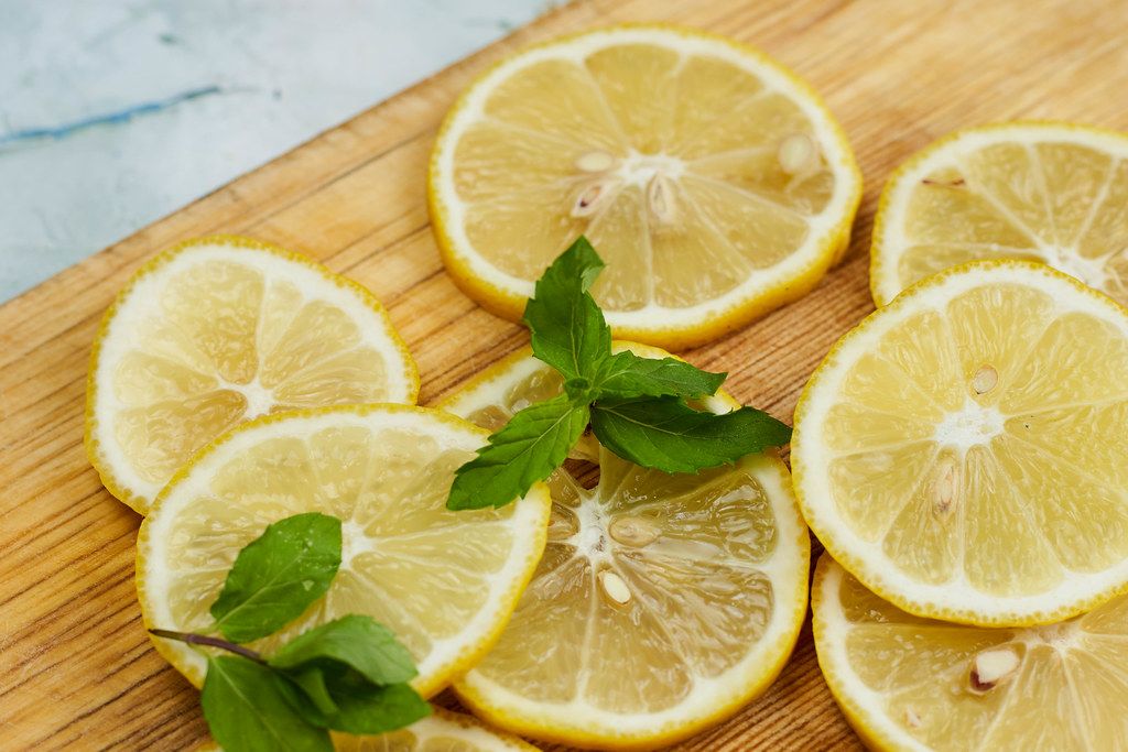 Tinny slices of fresh lemon with mint leafs on the cutting board
