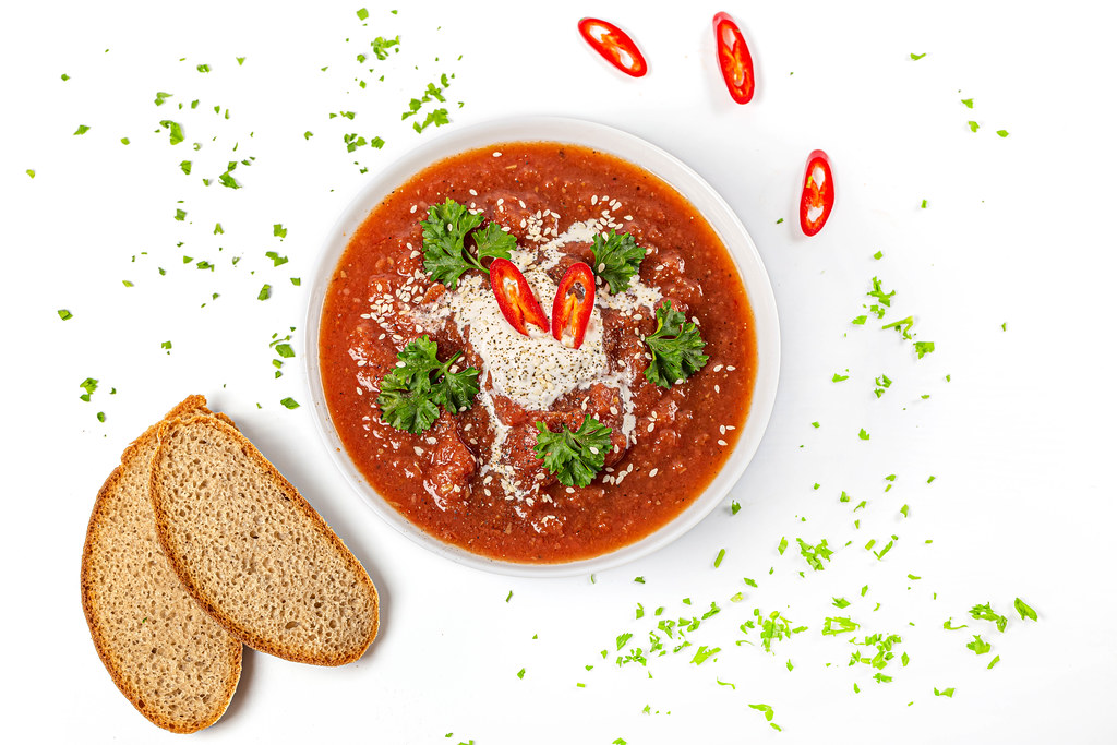 Tomato puree soup with parsley, spicy chili and sesame seeds, top view