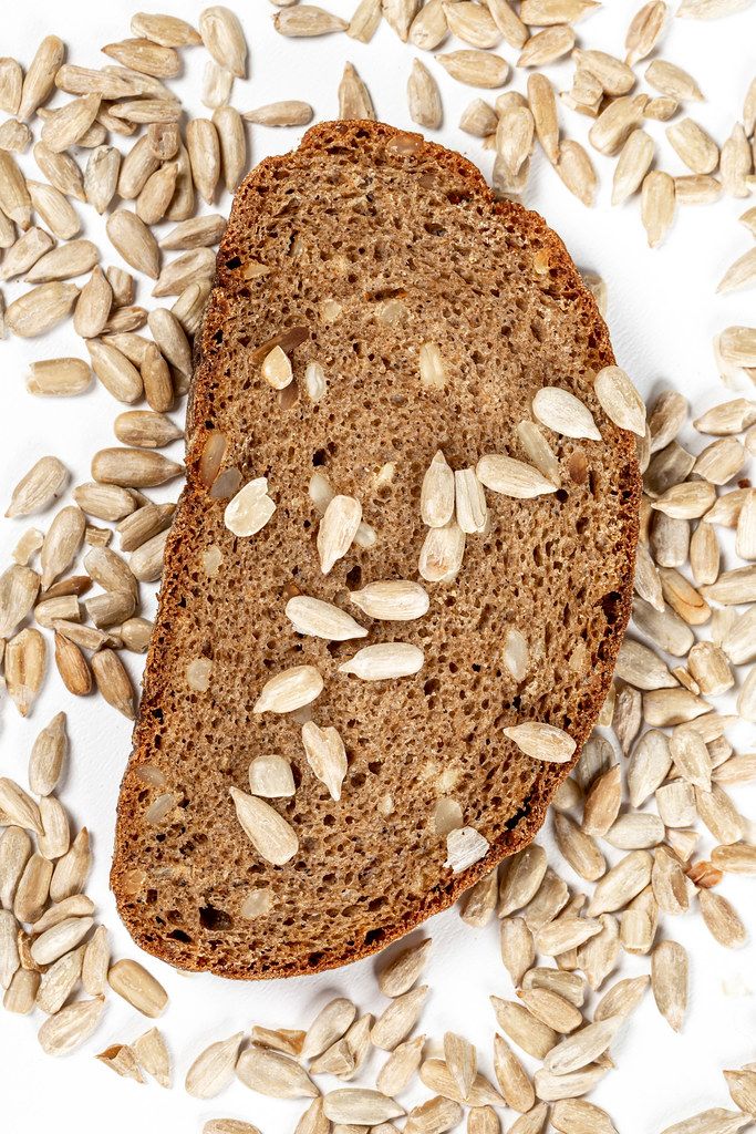 Top view, a piece of rye bread with sunflower seeds on a white background