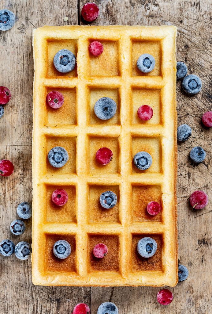 Top view, belgium waffles with blueberries and red currants on wooden background