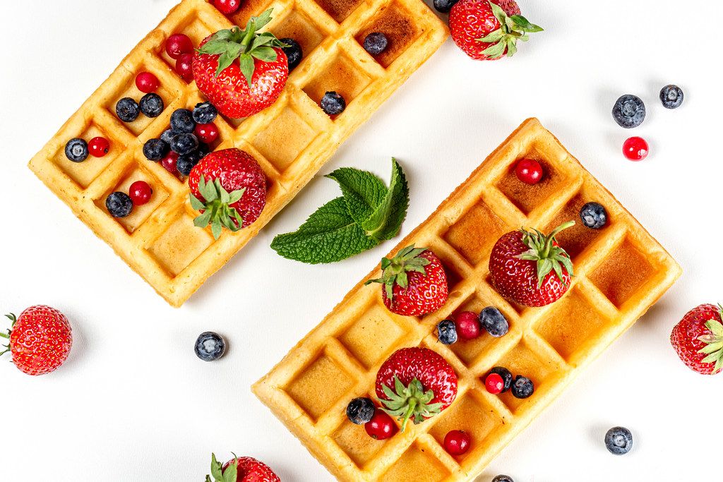 Top view, belgium waffles with fresh berries and mint leaves on a white background