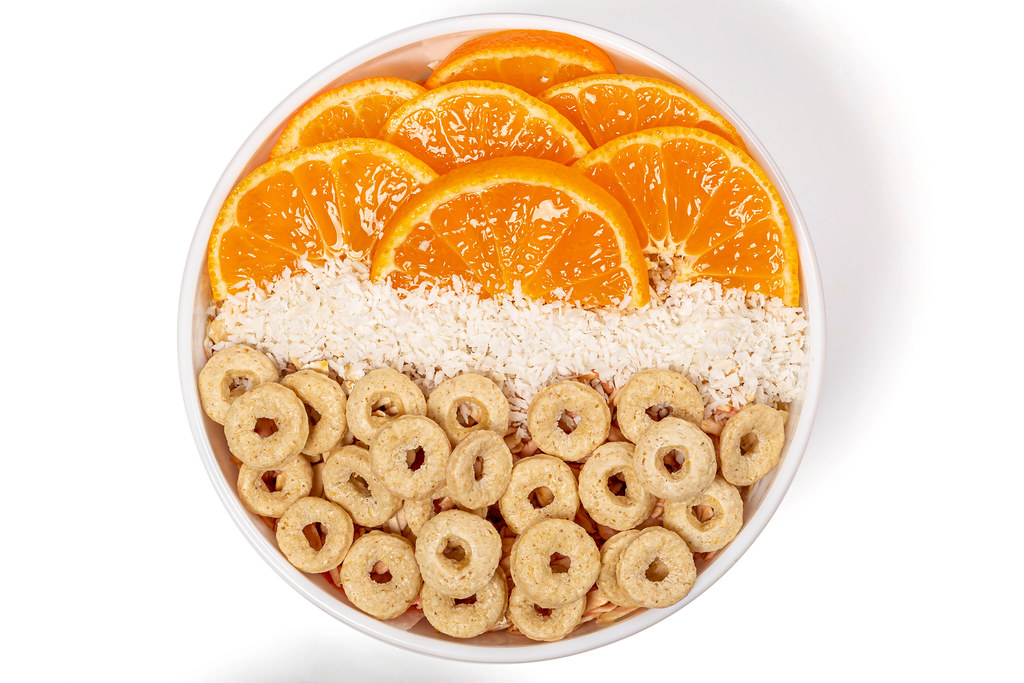 Top view, breakfast with multi-grain rings, tangerine pieces and coconut flakes