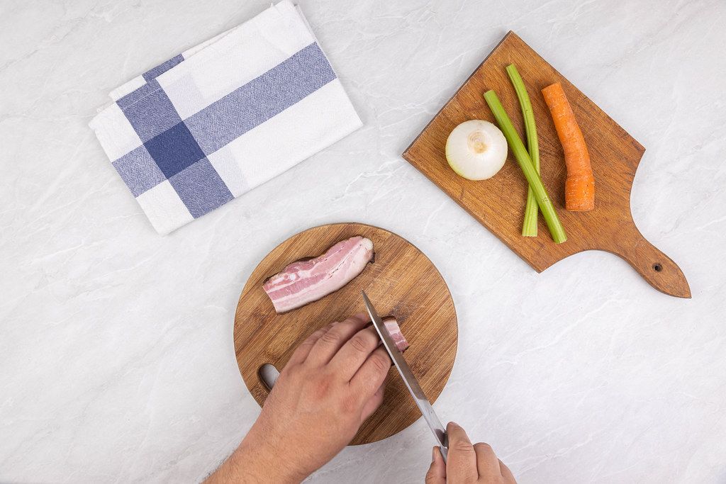 Top view Chef hands cutting Bacon on the wooden board