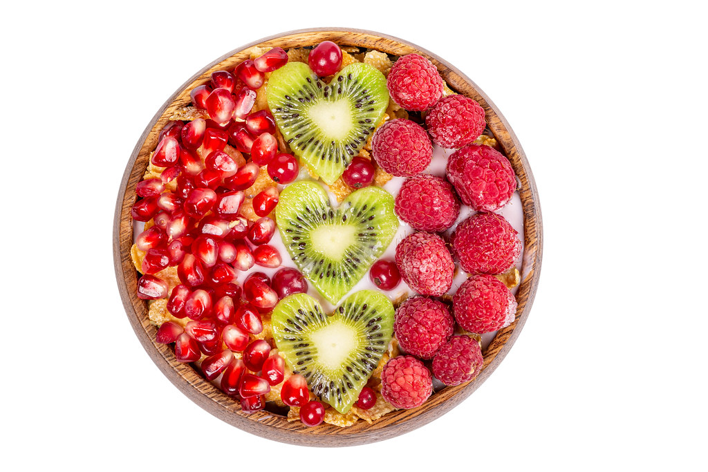 Top view, cornflakes with yogurt, berries and kiwi hearts