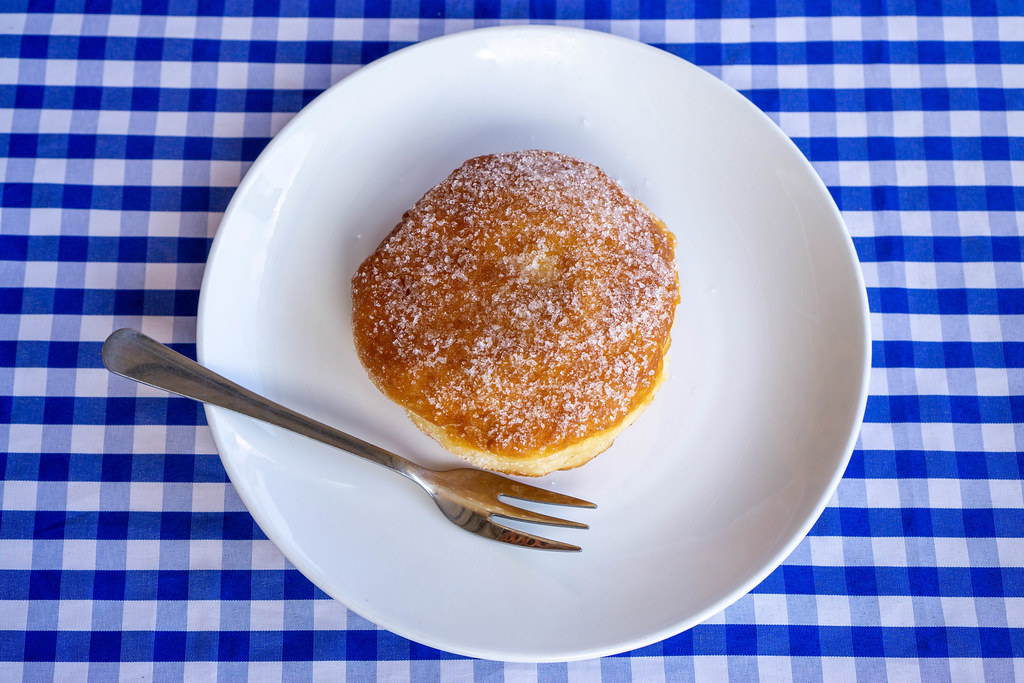 Top View Food Photo of Berliner German Doughnut topped with Sugar on a Plate with a Fork
