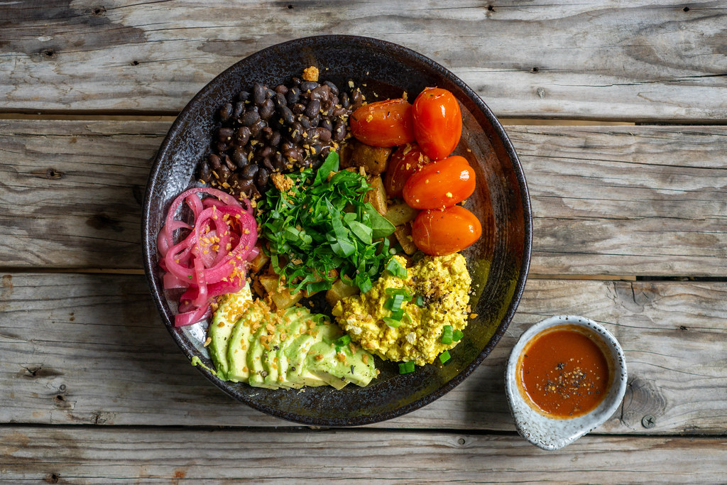 Top View Food Photo of Healthy Brekfast with Scrambled Eggs, Avocado Slices, Cherry Tomatoes, Kidney Beans and Baked Potatoes on a Wooden Table with Curry Sauce