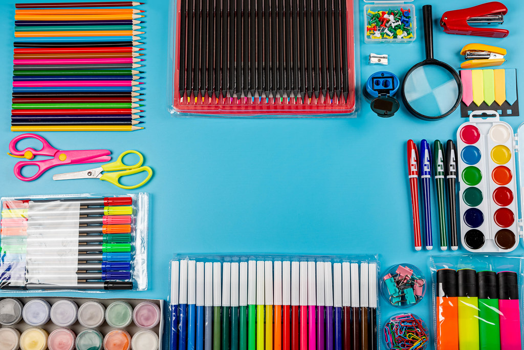 Top view, frame of colorful school supplies on a blue background