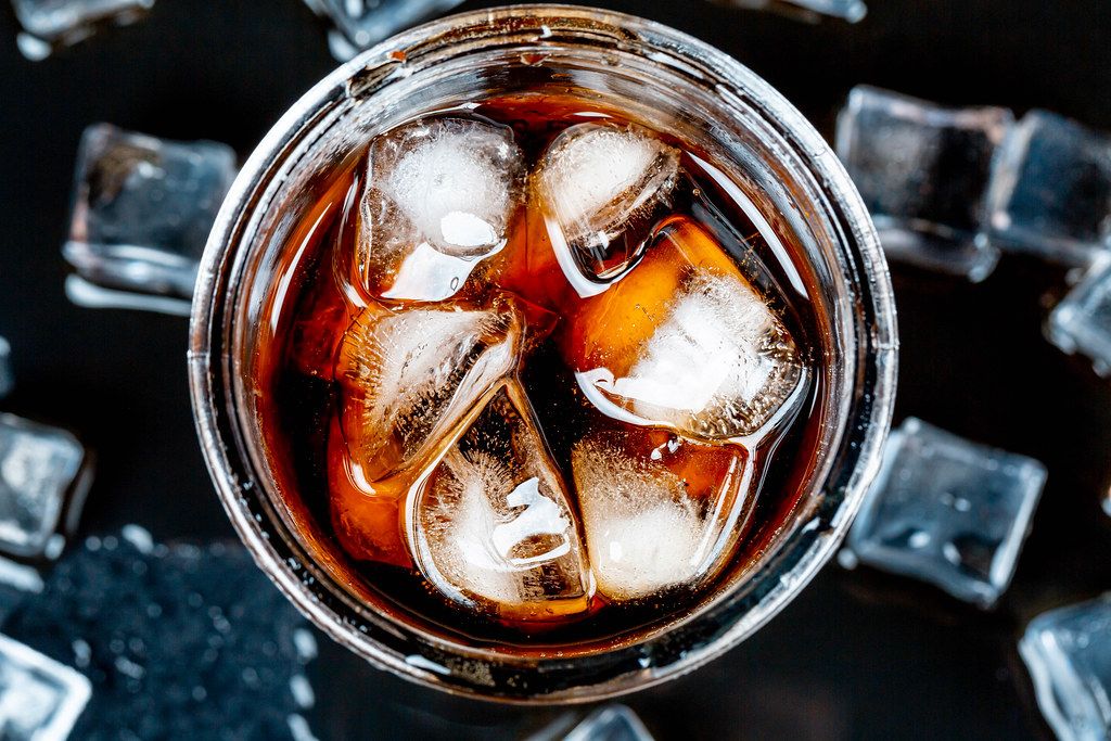 Top view, glass of cold drink with ice cubes on a black background