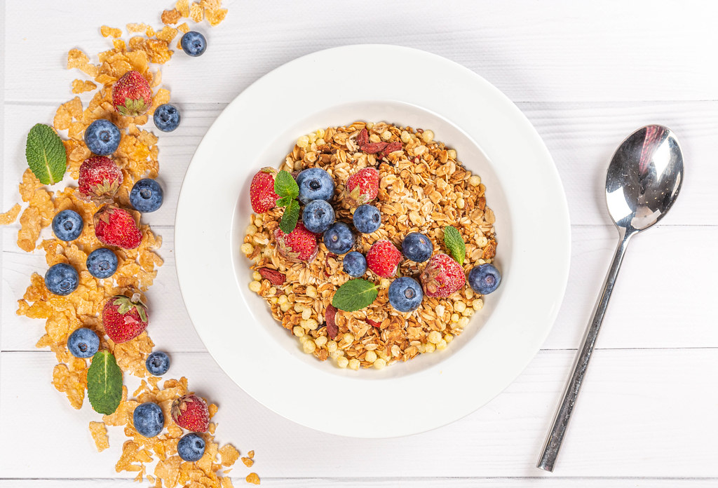 Top view, multigrain breakfast on wooden white background with strawberries, blueberries and mint leaves