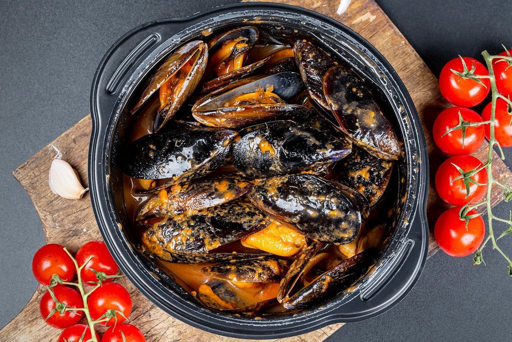 Top view, mussels with garlic and tomato sauce in a black pan