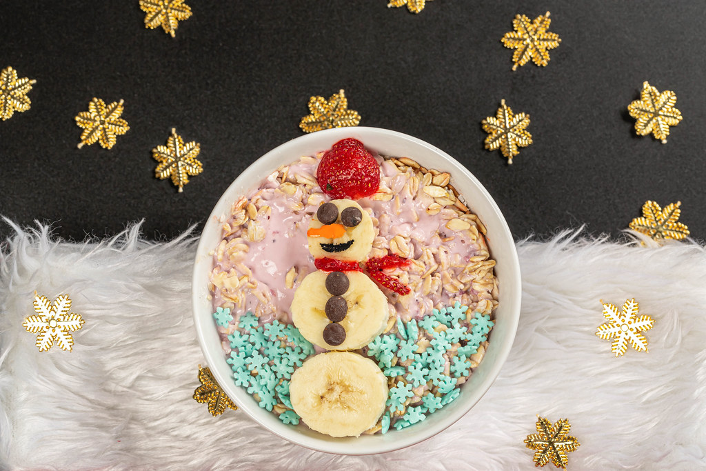 Top view oatmeal with yogurt and snowman made from slices of banana and strawberry