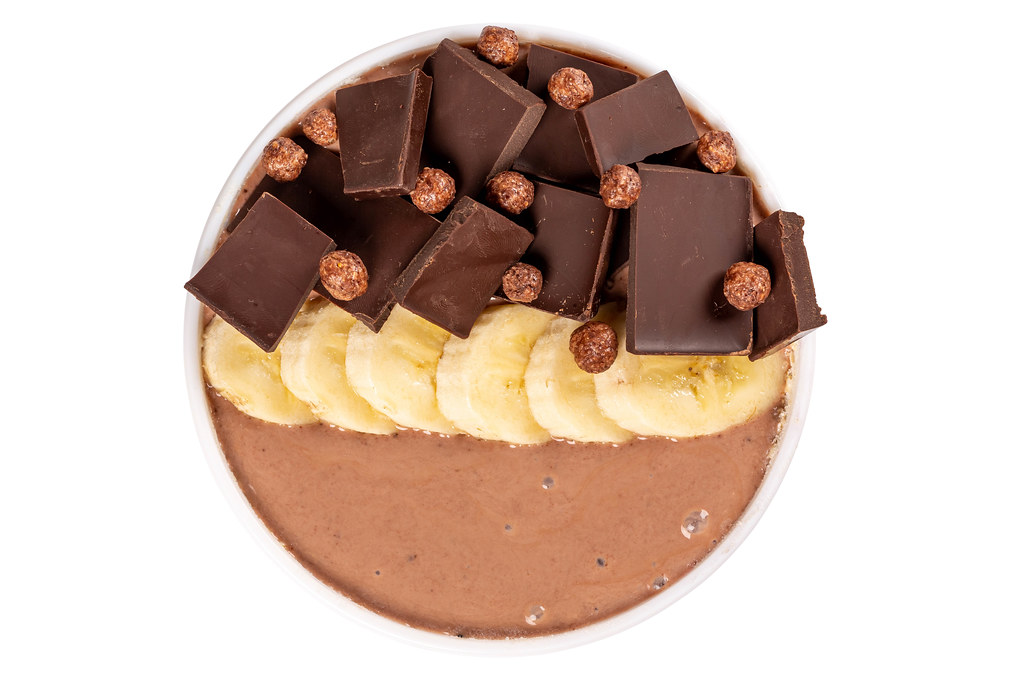 Top view, oatmeal with yogurt, banana slices and dark chocolate