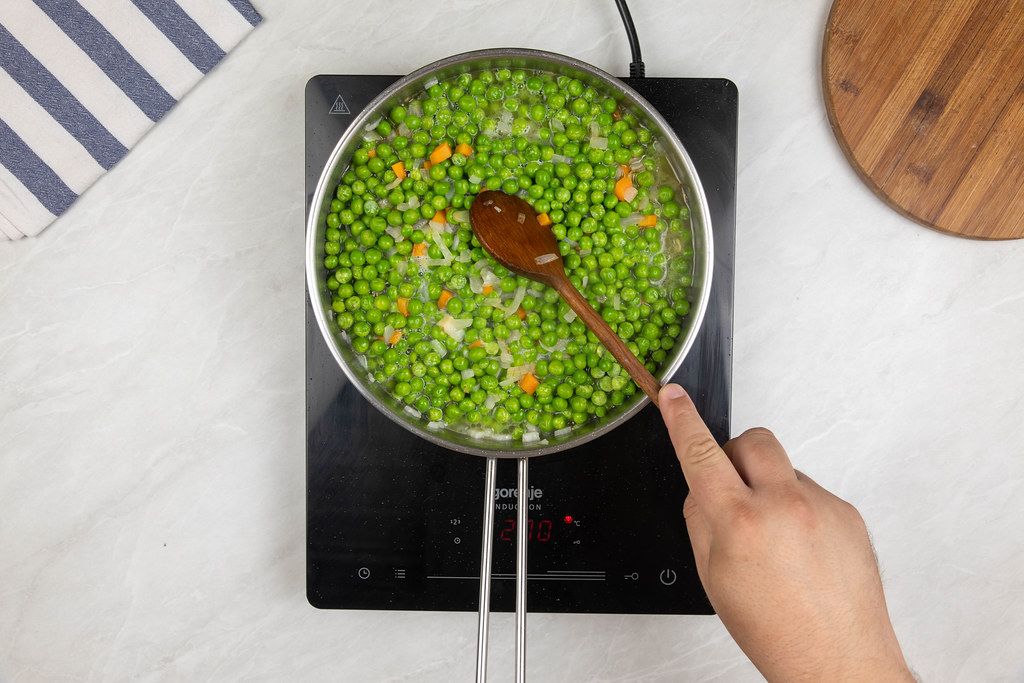 Top view of Frying pan with cooking Green Peas