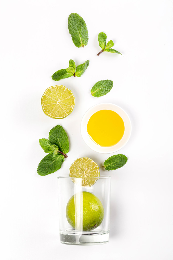 Top view of glass with lime, mint and honey on white background, beverage preparation concept